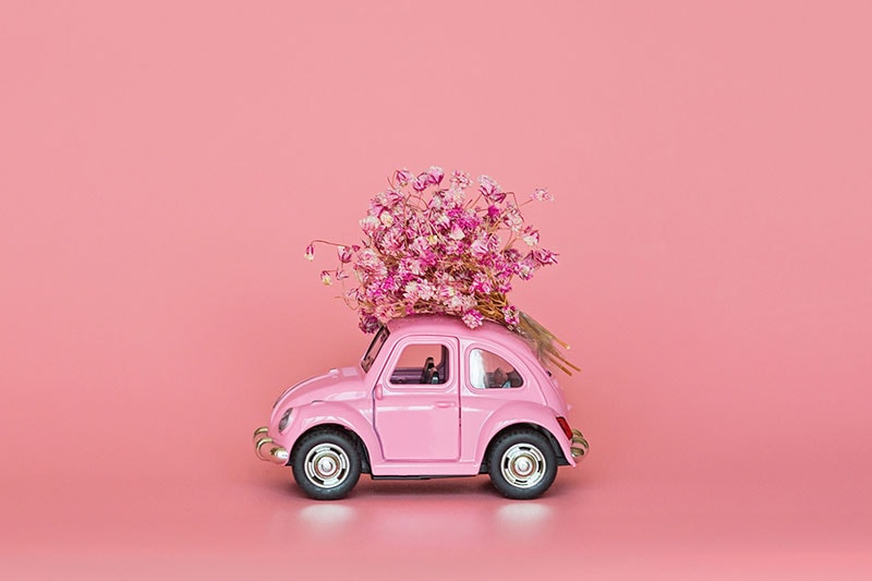Roze automobil sa cvećem na krovu