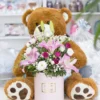 Flower box sačinjen od roze ljiljana, roze ruža i ljubičastih i belih lizijantusa sa medom u pozadini Flower box sačinjen od roze ljiljana, roze ruža i ljubičastih i belih lizijantusa sa medom u pozadini