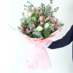 Buket sa roze ruzama i roze ljiljanima upakovan u roze papiru sa zelenilom